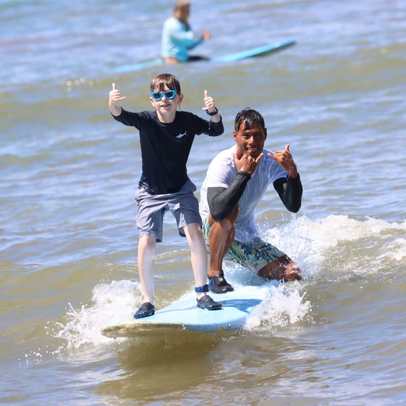 a man and a woman riding a wave on a surfboard in the water