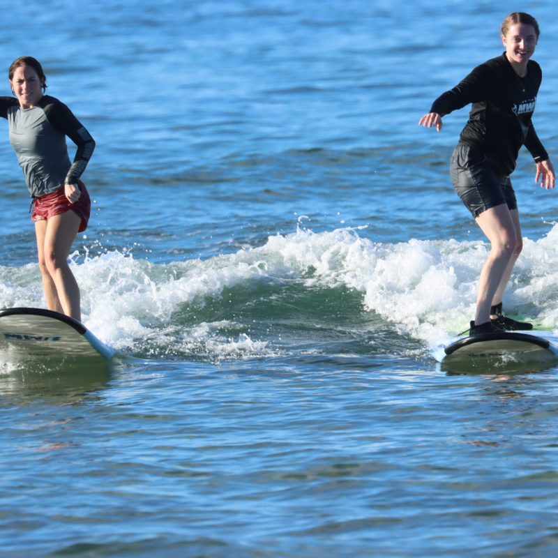a man and a woman riding a wave on a surfboard in the water