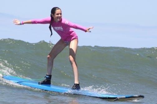 a young girl riding a wave on a surfboard in the water