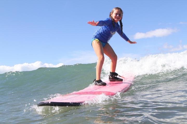 a young girl riding a wave on a surfboard in the water